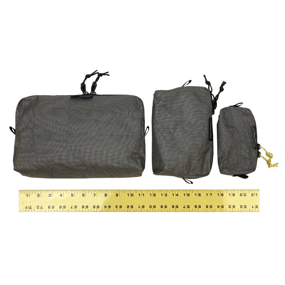 Left to right: A large, medium, and small EcoPak Ultra Packing Cube sit next to a measuring tape. The large is approx. 11" in length, the medium is appro. 5" tall, and the small is approx. 3" tall.