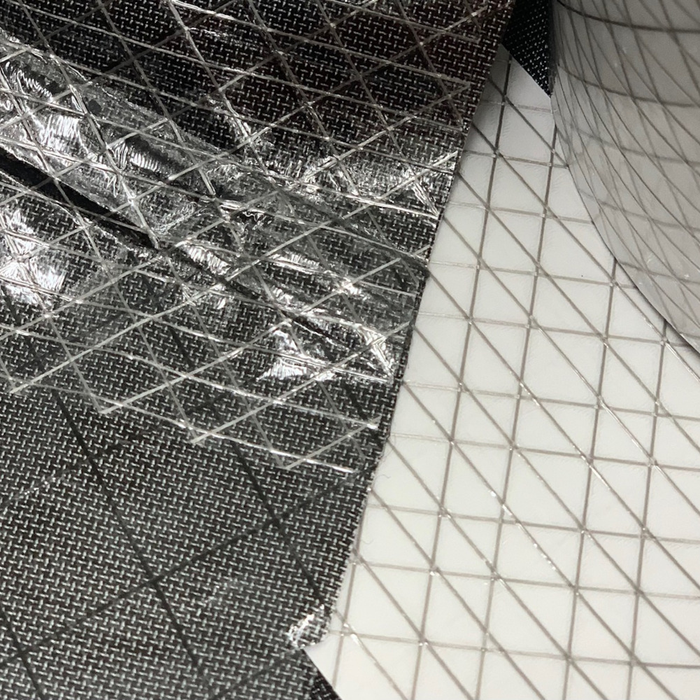 A piece of Ultra TNT Repair + Seal Seam Tape being used to repair technical fabric